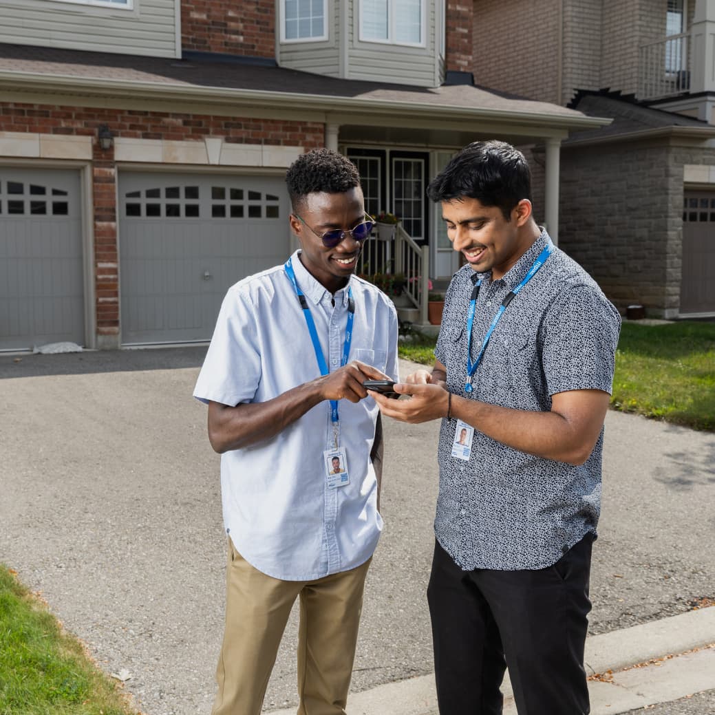 Two MPAC employees in front of a residential house